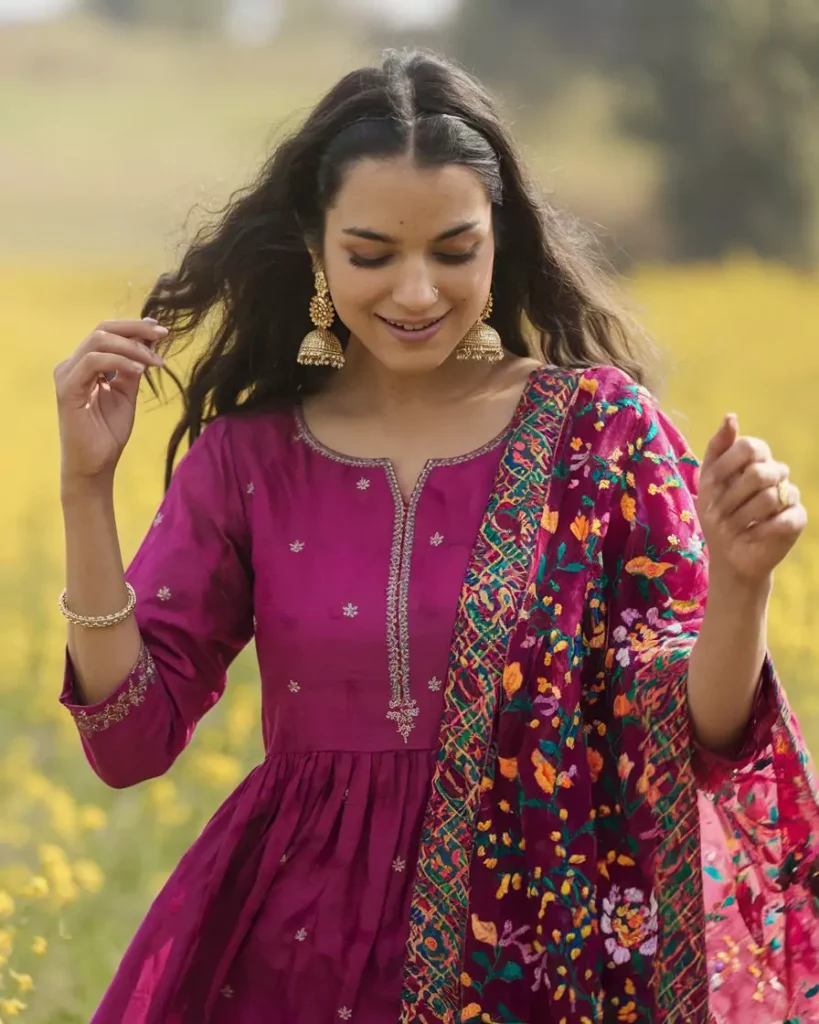 Prompts to Create Beautiful Indian Girls in Diverse Indian Attires AI-generated image of a beautiful Indian girl in a vibrant magenta Patiala Salwar Kameez with intricate embroidery and a floral dupatta, accessorized with traditional Punjabi jewelry, standing amid mustard fields, celebrating the lively spirit and cultural heritage of Punjab by AI Artz.