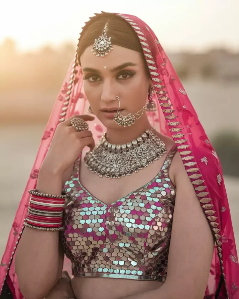 Prompts to Create Beautiful Indian Girls in Diverse Indian Attires AI-generated image of a beautiful Indian girl wearing a dazzling mirror-work Ghagra Choli with a vibrant pink dupatta and heavy silver jewelry, representing Rajasthan's colorful traditions and festive attire in a sunset desert setting by AI Artz.