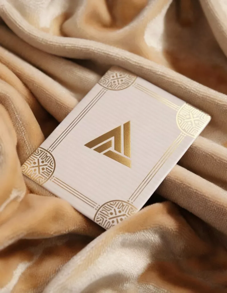 Create Custom AI Images for Coffee Shop Branding AI-generated coffee shop branding image featuring a gold-foil AI Artz and AI Art Revolution Loyalty Card Design logo on a textured white card with ornate golden borders, placed on soft beige velvet fabric by AI Artz